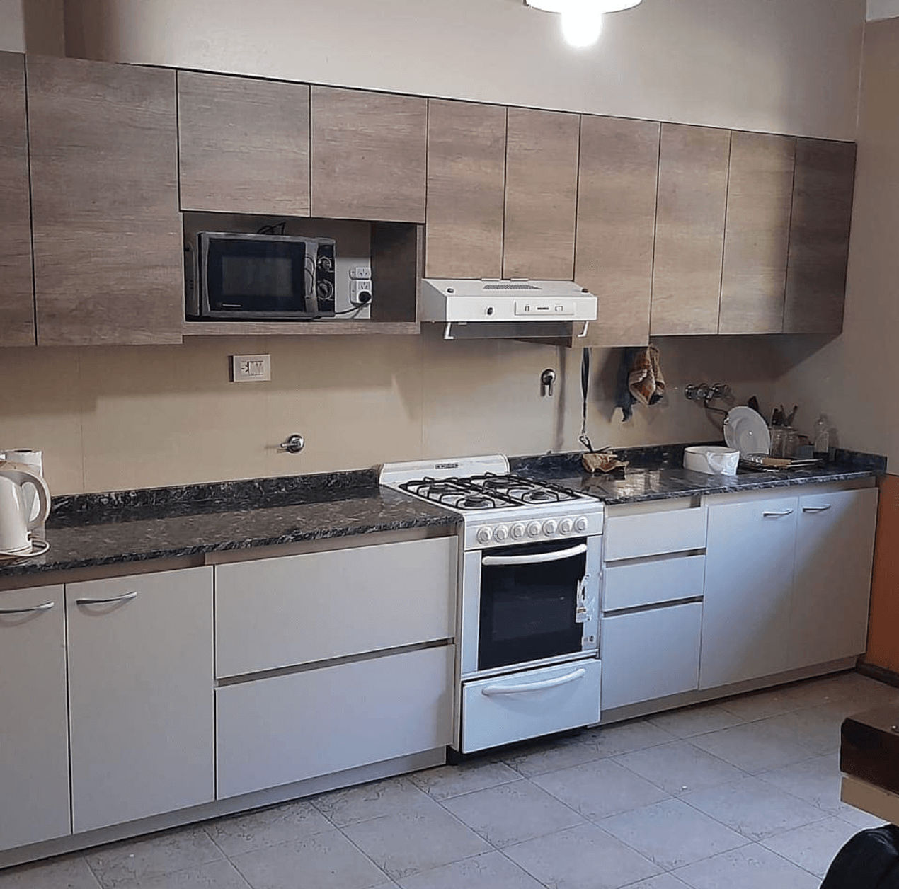 Cocina lineal con muebles superiores y mesada de granito